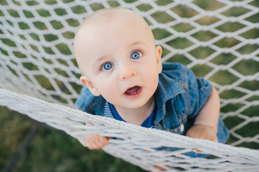 close up of baby boy looking at camera while climbing in a hammock