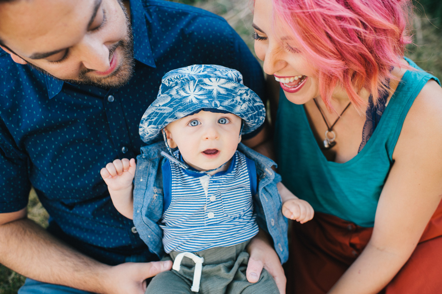 mom and dad holding baby son who is looking at camera