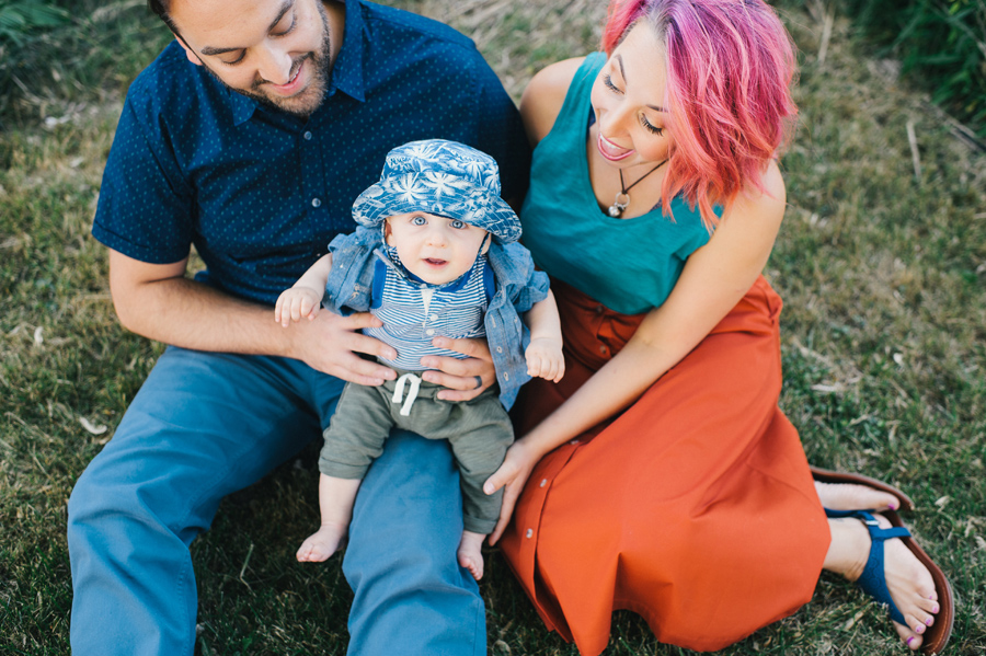 baby boy sitting with parents on the lawn