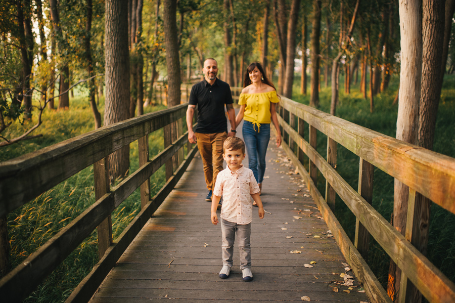 family walking on a bridge in the woods towards the camera 