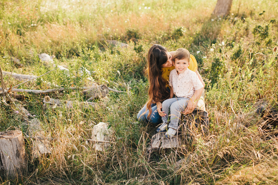 mom whispering in son's ear as he smiles at camera