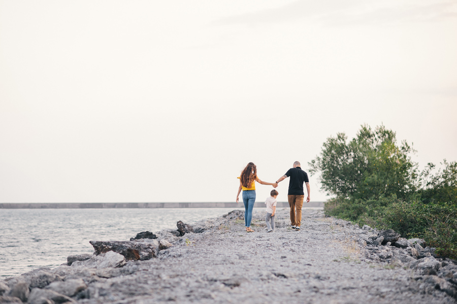 husband and wife holding hands while son walks between them away from camera