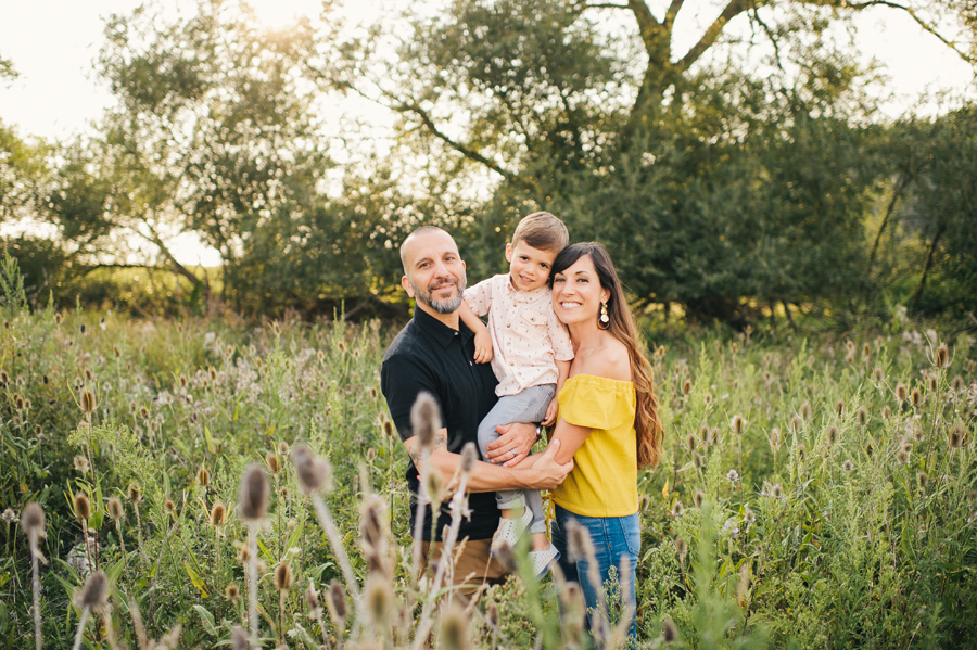 family smiling at the camera in a field